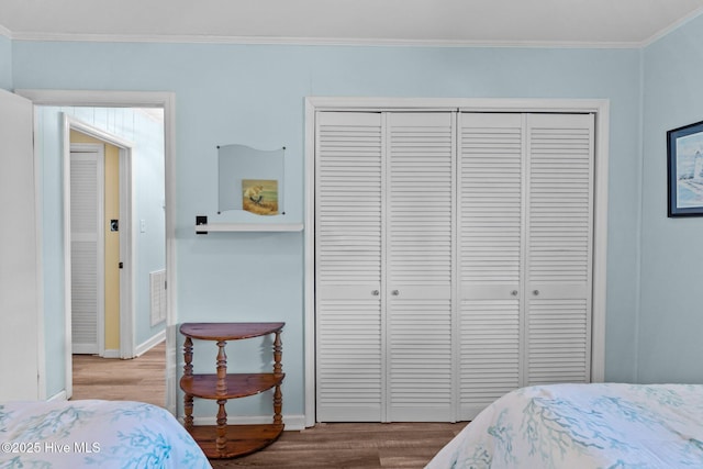 bedroom featuring crown molding, baseboards, a closet, and wood finished floors