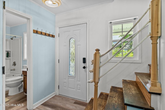 entrance foyer with stairway, baseboards, crown molding, and wood finished floors