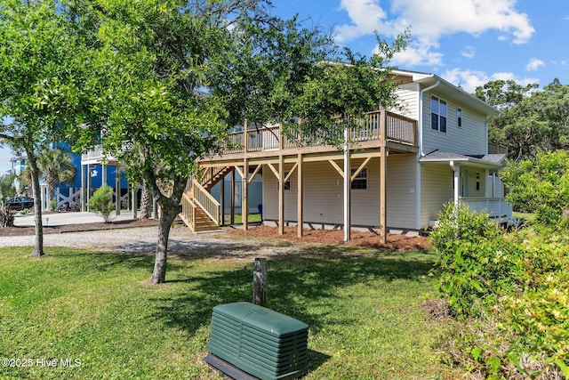 back of house featuring a lawn, a wooden deck, and stairs