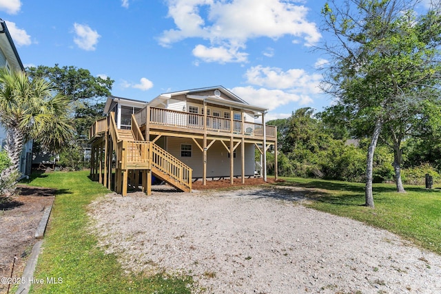 rear view of house with a wooden deck, stairs, and a lawn