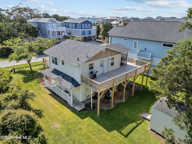 back of house with a lawn, a deck, a residential view, and roof with shingles