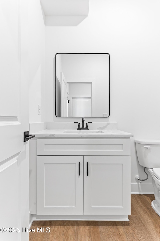 322 NE 50th St, Oak Island, NC 28465 - half bathroom featuring toilet, baseboards, wood finished floors, and vanity