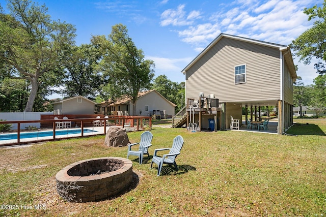 view of yard with a fire pit, a deck, a patio, stairs, and a fenced in pool