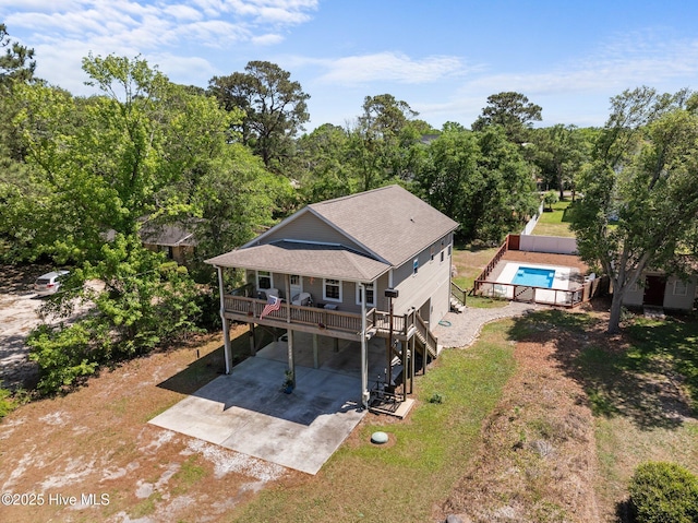 back of house with driveway, a wooden deck, a carport, a yard, and a shingled roof
