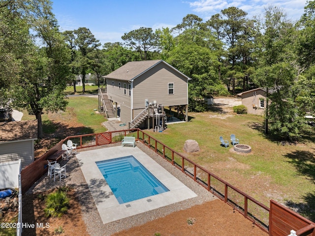view of swimming pool featuring stairway, a fenced in pool, a lawn, a patio, and a fire pit