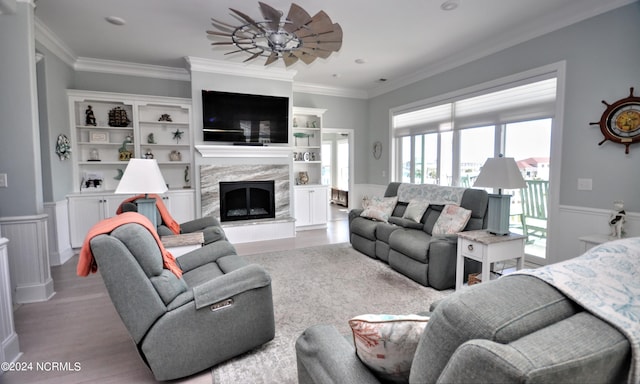 living room featuring ornamental molding, wood finished floors, a premium fireplace, and a wainscoted wall