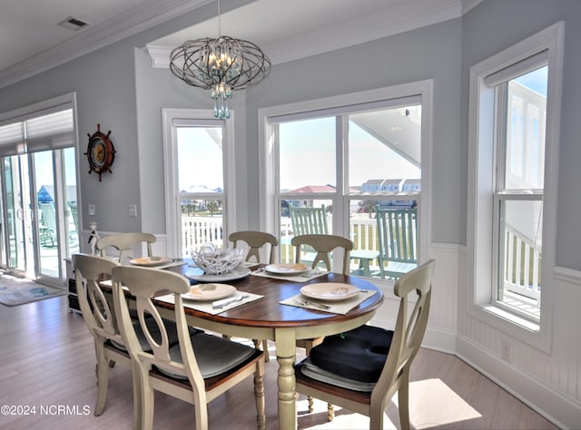 dining area featuring ornamental molding, a chandelier, a healthy amount of sunlight, and light wood-style flooring