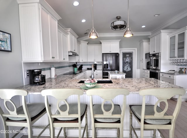 kitchen featuring decorative backsplash, ornamental molding, a peninsula, a sink, and black appliances