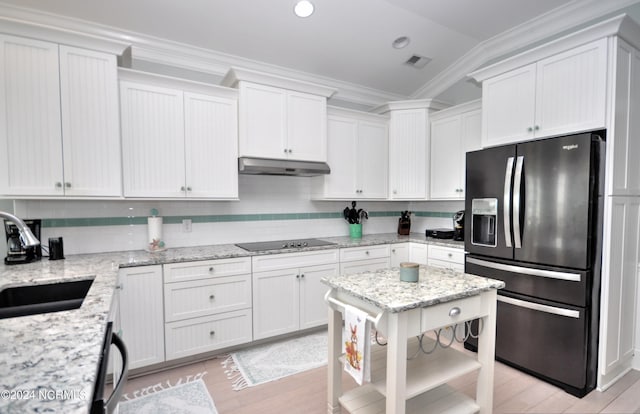 kitchen featuring visible vents, under cabinet range hood, a sink, light wood-style flooring, and black appliances