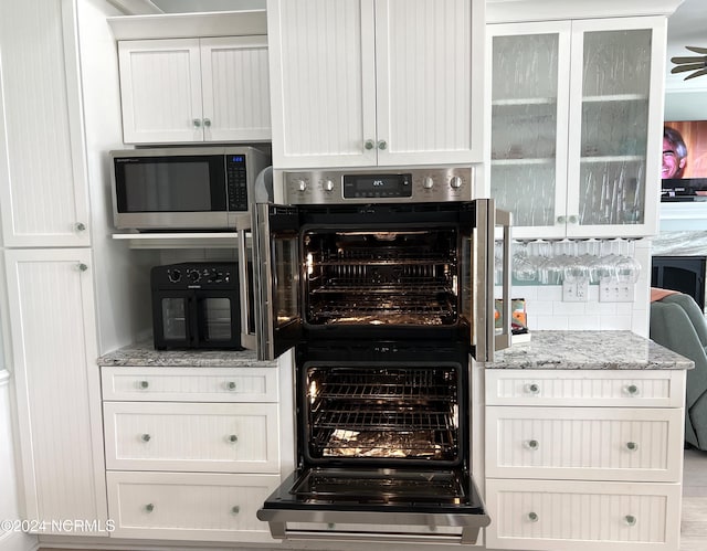 kitchen featuring light stone counters, white cabinetry, and stainless steel microwave