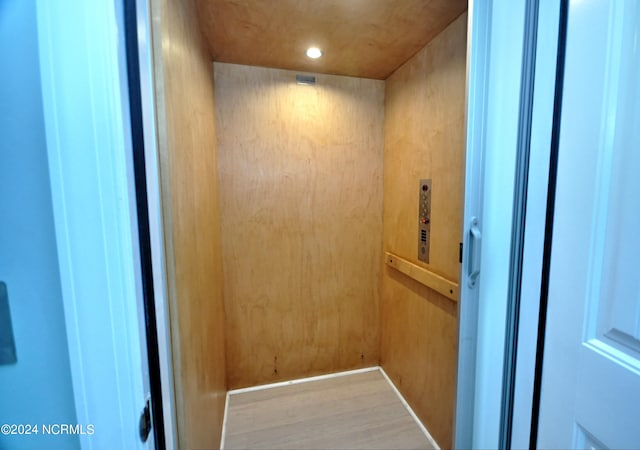 interior details featuring recessed lighting, elevator, and wood finished floors