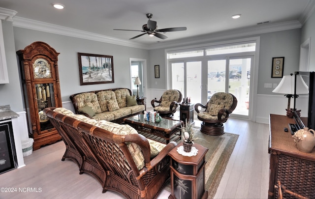 living room featuring crown molding, a ceiling fan, light wood-type flooring, and visible vents