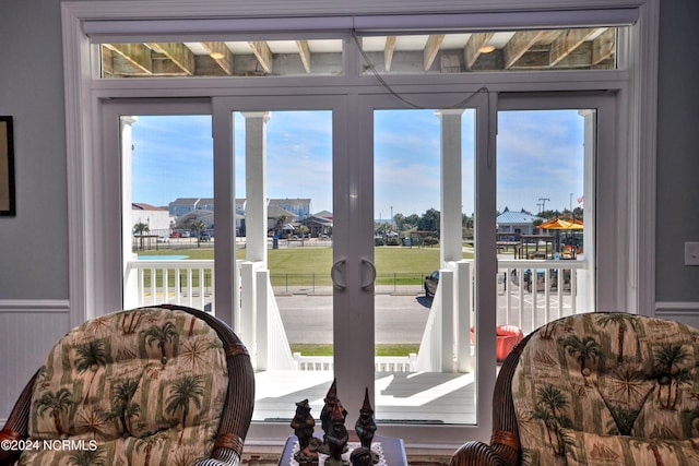 doorway to outside with a healthy amount of sunlight and a wainscoted wall
