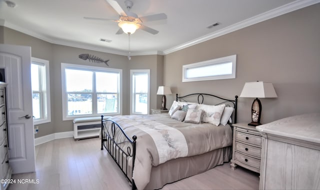 bedroom featuring baseboards, ornamental molding, light wood finished floors, and visible vents