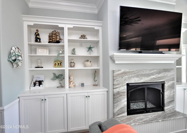 living room with ornamental molding, built in shelves, and a premium fireplace