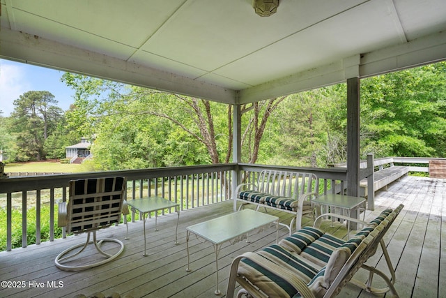 wooden deck with view of scattered trees and an outdoor hangout area