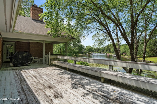 wooden deck with a water view and a grill