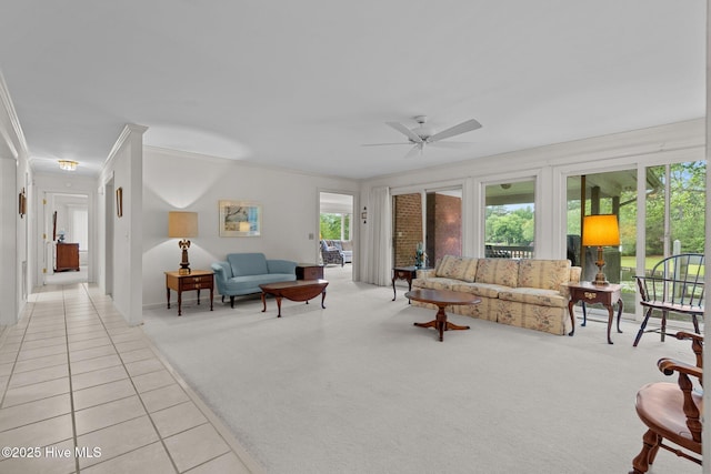 living area with ornamental molding, plenty of natural light, light colored carpet, a ceiling fan, and light tile patterned floors