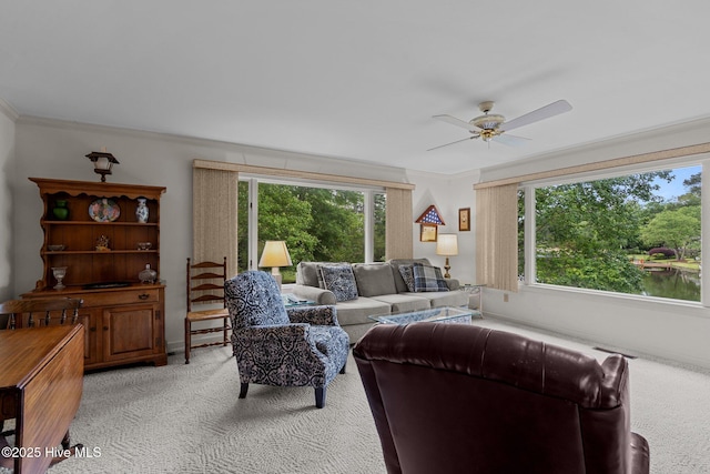 living area featuring light carpet, plenty of natural light, a ceiling fan, and ornamental molding