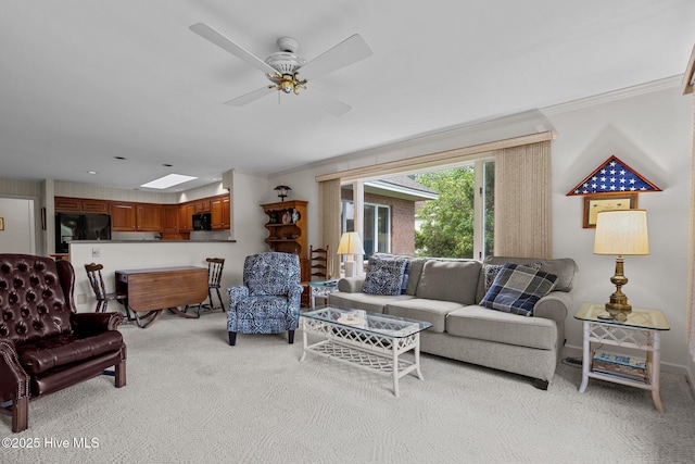 living area with light carpet, ornamental molding, a ceiling fan, and a skylight