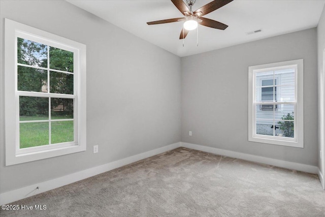 carpeted spare room featuring baseboards, visible vents, and a ceiling fan