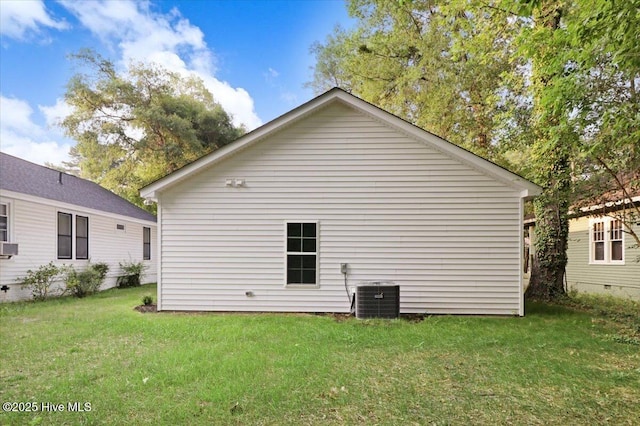 rear view of property with central AC unit and a lawn