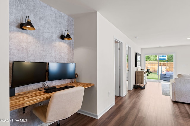office space featuring baseboards, wood finished floors, and an accent wall