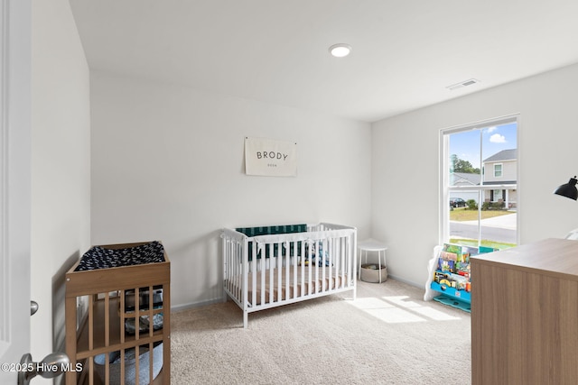 carpeted bedroom with a nursery area and visible vents