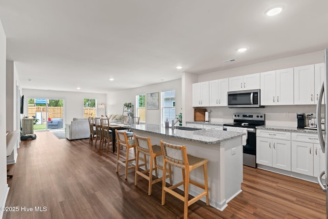 kitchen featuring a kitchen island with sink, visible vents, appliances with stainless steel finishes, a sink, and white cabinetry