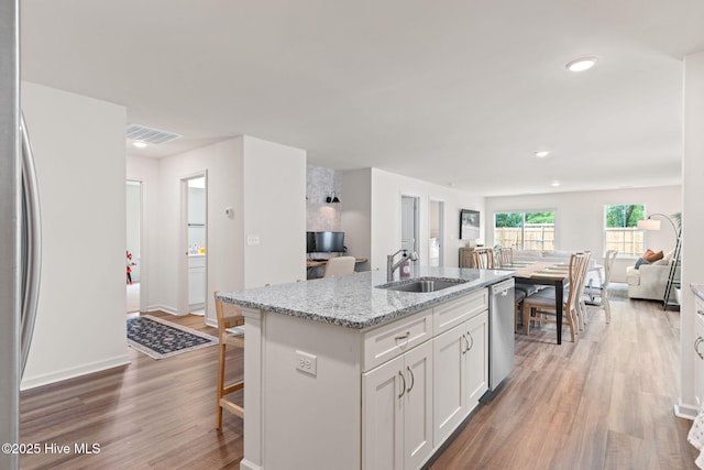 kitchen featuring light wood-type flooring, a sink, appliances with stainless steel finishes, and open floor plan