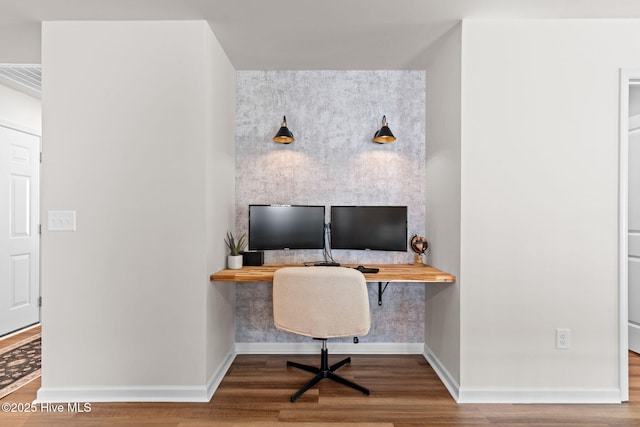 home office with baseboards, built in study area, and wood finished floors