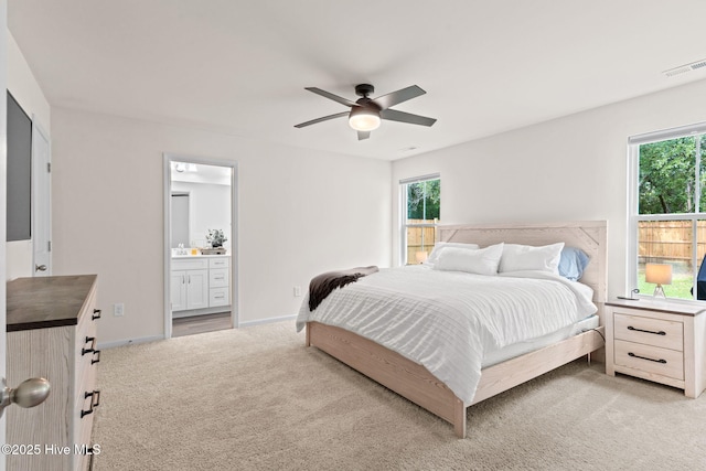bedroom with connected bathroom, light carpet, a ceiling fan, baseboards, and visible vents
