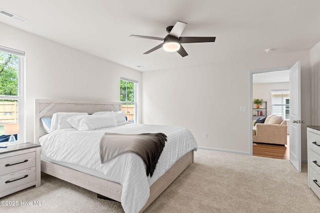 bedroom featuring baseboards, a ceiling fan, light colored carpet, and visible vents