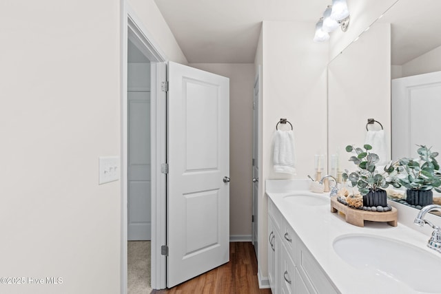 full bath featuring a sink, double vanity, and wood finished floors