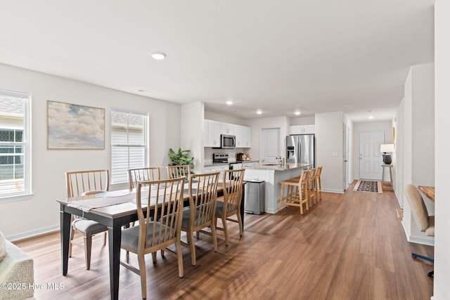 dining space featuring light wood-type flooring, recessed lighting, baseboards, and a wealth of natural light