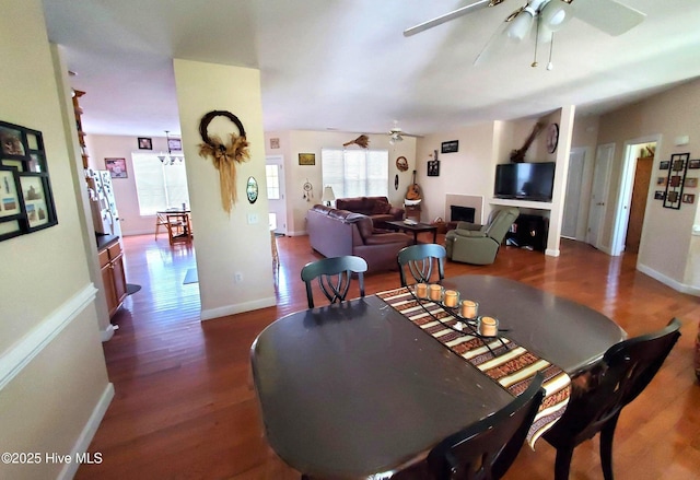 dining area with baseboards, ceiling fan, and dark wood-style floors