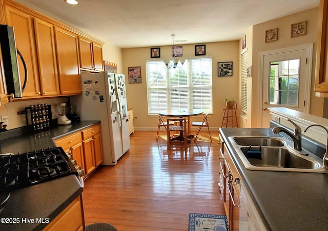 kitchen featuring light wood-type flooring, a sink, stainless steel microwave, and dark countertops