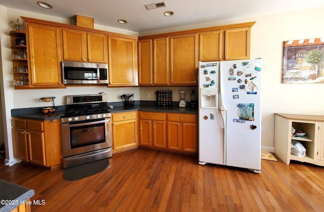 kitchen featuring dark countertops, brown cabinetry, stainless steel appliances, and visible vents