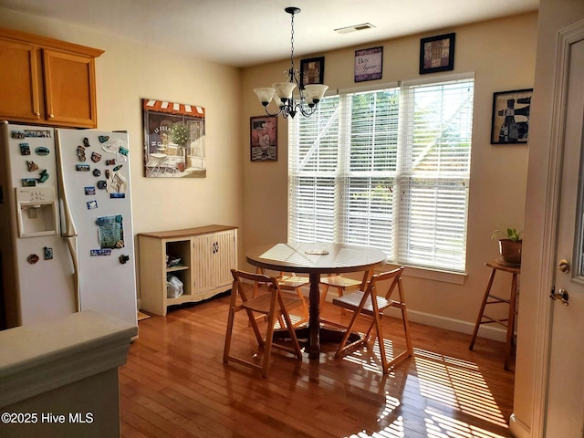 dining room with a wealth of natural light, wood-type flooring, a notable chandelier, and visible vents