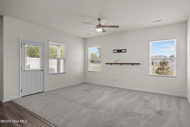 carpeted spare room with visible vents, a ceiling fan, and baseboards