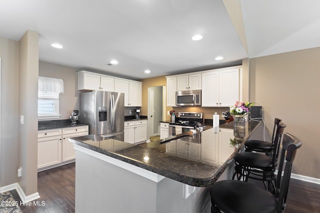 743 Heather Glen Ln, Calabash, NC 28467 - kitchen with a breakfast bar, white cabinetry, a peninsula, dark wood-type flooring, and stainless steel appliances