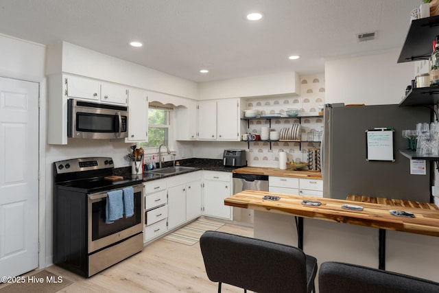 kitchen with wooden counters, visible vents, appliances with stainless steel finishes, a sink, and white cabinets
