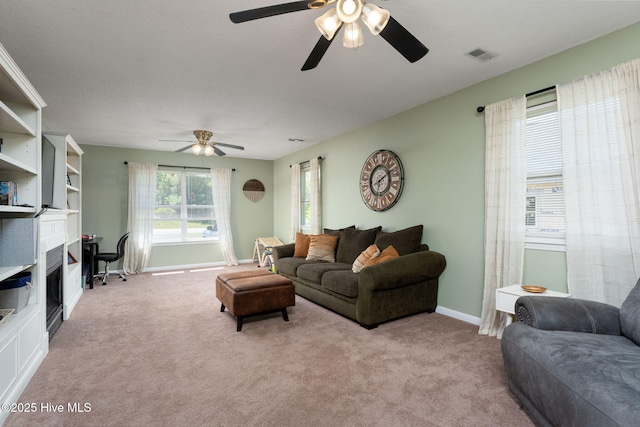 carpeted living room with baseboards, a ceiling fan, and visible vents