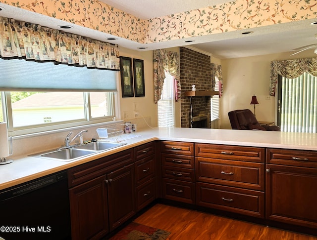 kitchen featuring light countertops, black dishwasher, a brick fireplace, and a sink