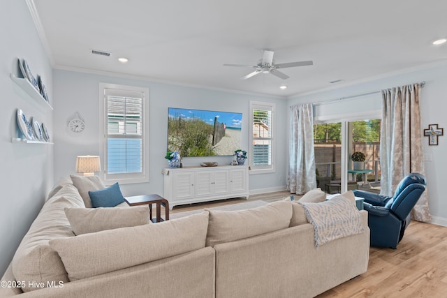 living room with visible vents, ornamental molding, baseboards, and a healthy amount of sunlight