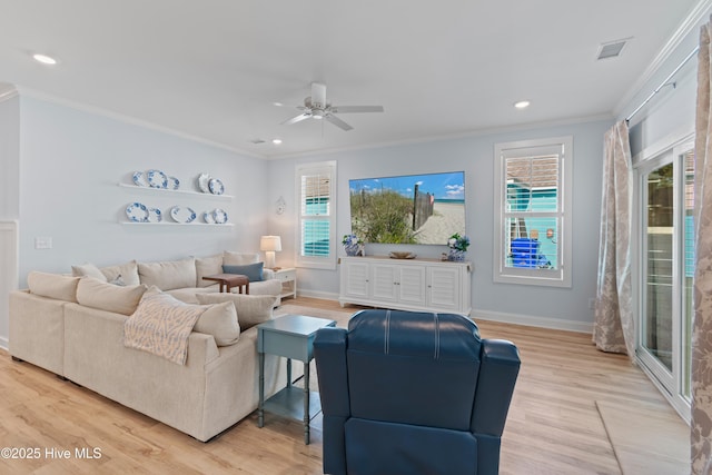 living room featuring a ceiling fan, ornamental molding, and light wood finished floors