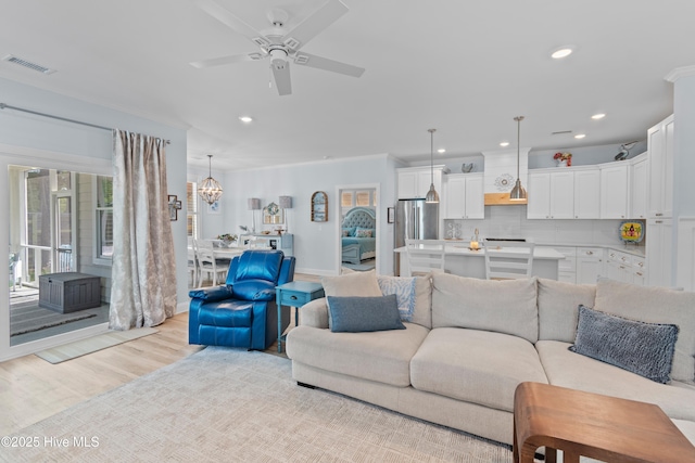 living area featuring visible vents, recessed lighting, light wood finished floors, and ceiling fan with notable chandelier