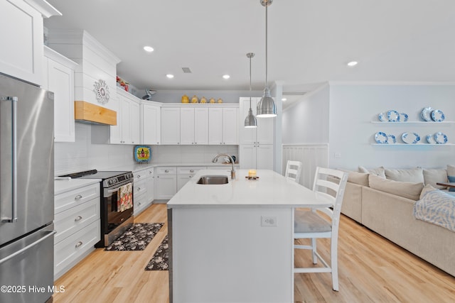 kitchen featuring crown molding, a kitchen breakfast bar, light countertops, a sink, and stainless steel appliances