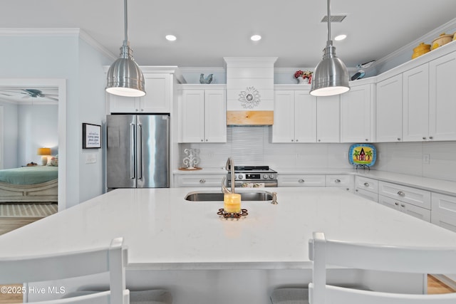 kitchen with appliances with stainless steel finishes, a sink, a kitchen island with sink, visible vents, and ornamental molding