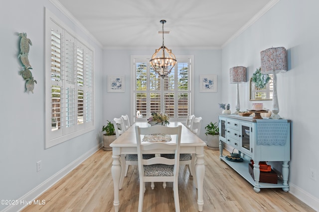 dining area with an inviting chandelier, light wood-style flooring, crown molding, and baseboards